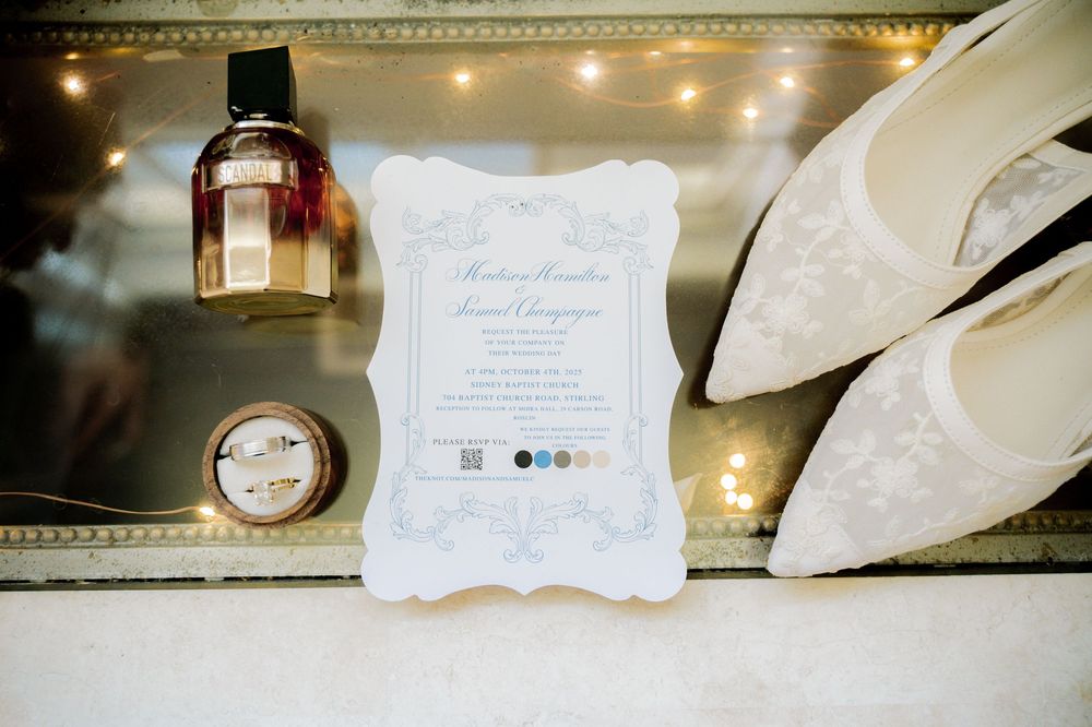 Elegant wedding invitation details with ornate calligraphy and decorative elements displayed on a light surface.