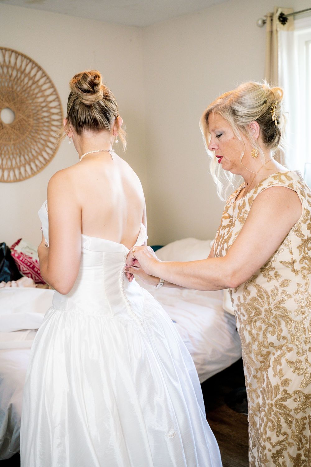 A bride in a white wedding gown gets help with final dress adjustments before her ceremony.