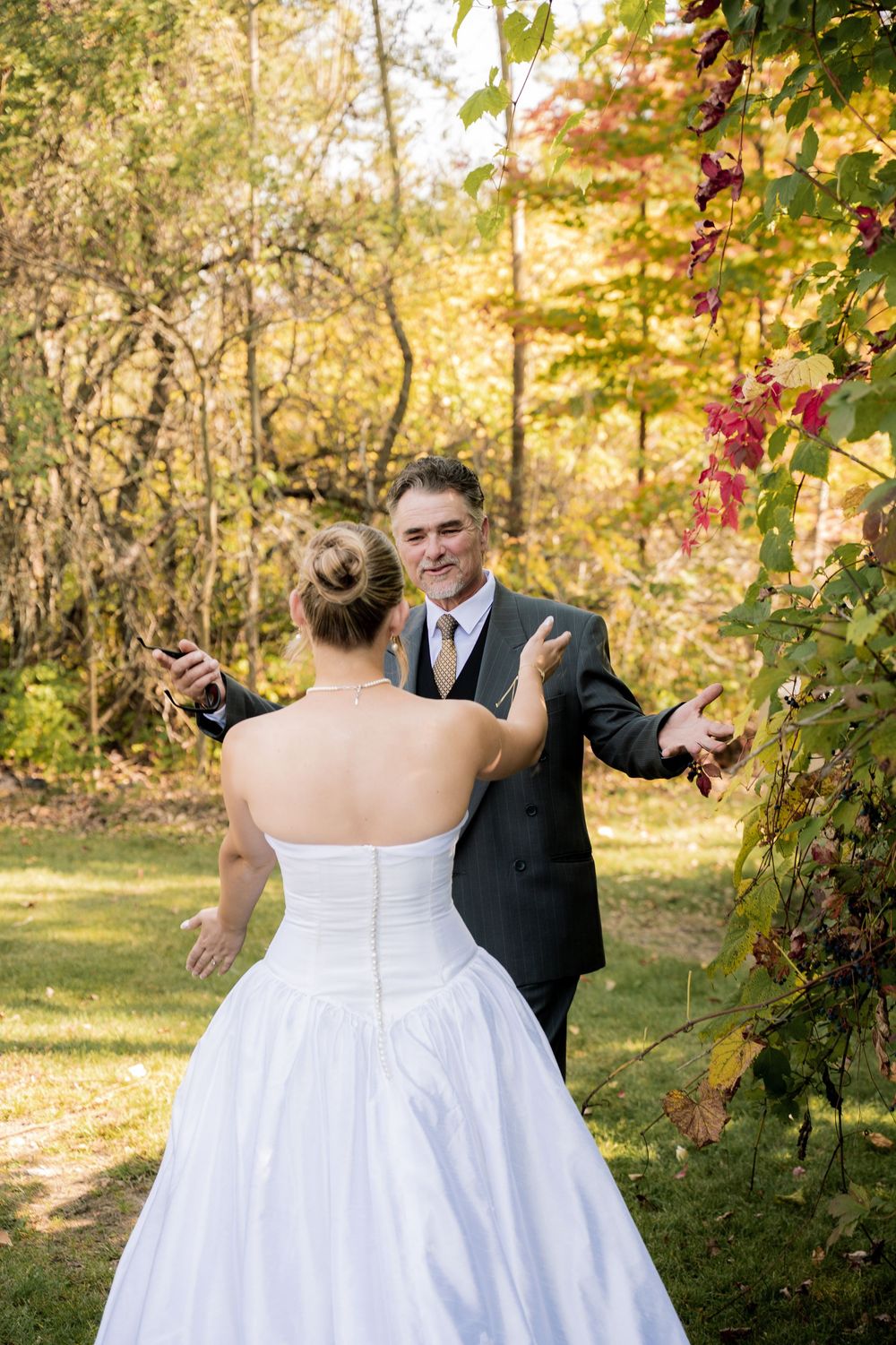 A couple shares a romantic dance moment in an autumn garden setting with golden foliage and sunlight.