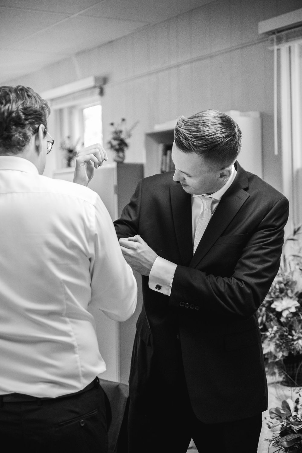 Black and white sequence showing two people in formal attire interacting in a hallway.