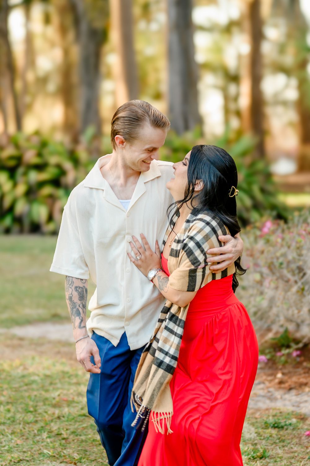 A couple shares a romantic moment in a park setting with golden sunlight filtering through trees.