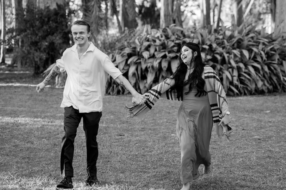 Black and white photo sequence of a couple walking and dancing playfully in a park setting.
