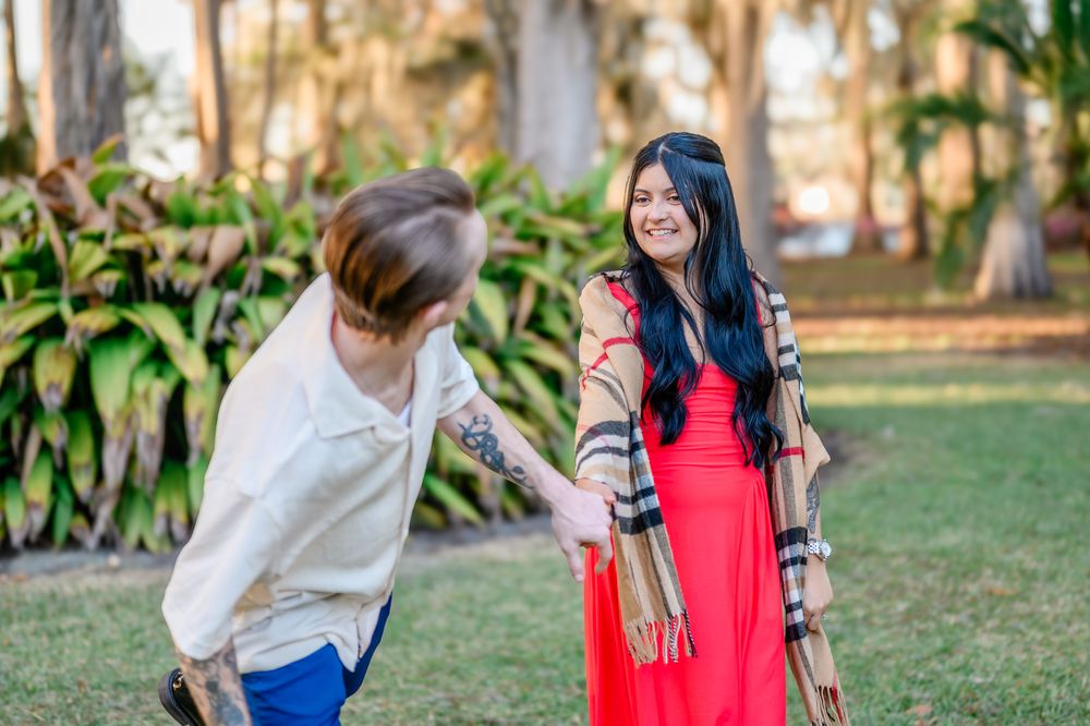Two people share a playful moment together in a garden setting with lush greenery and trees in the background.