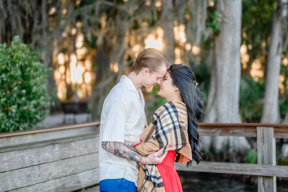 A couple shares an intimate moment on a wooden bridge surrounded by Spanish moss and greenery.