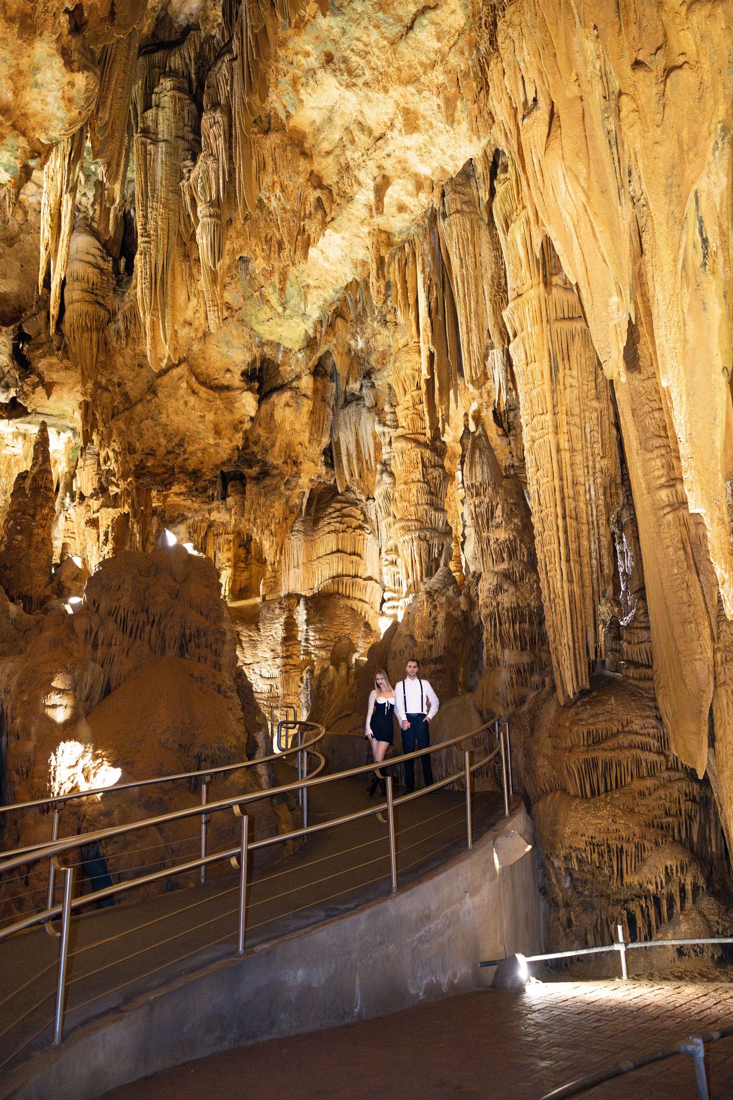 Illuminated limestone formations and stalactites line the walkway inside Natural Bridge Caverns in Texas.