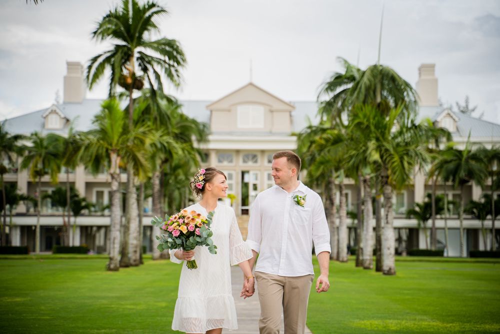Palm trees sway in front of elegant white colonial-style buildings on a tropical resort property. Shot by Luminair Studio