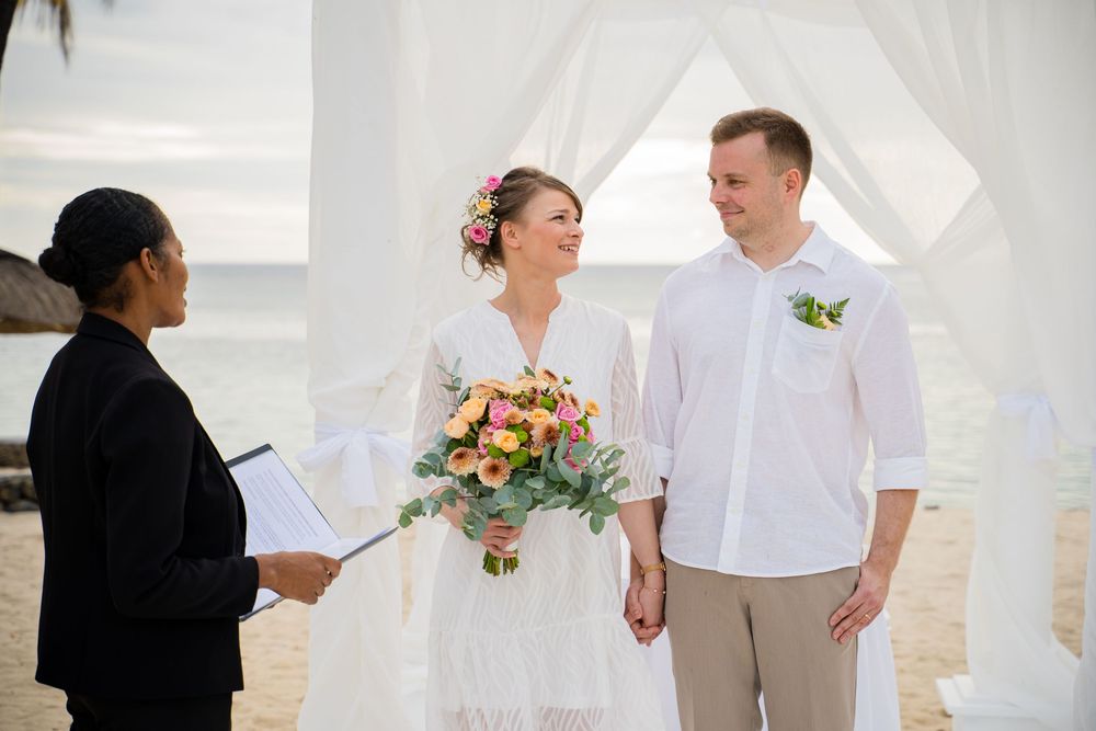 A series of beach wedding photos showing couples in white attire exchanging vows and celebrating by the ocean. Shot by Luminair Studio