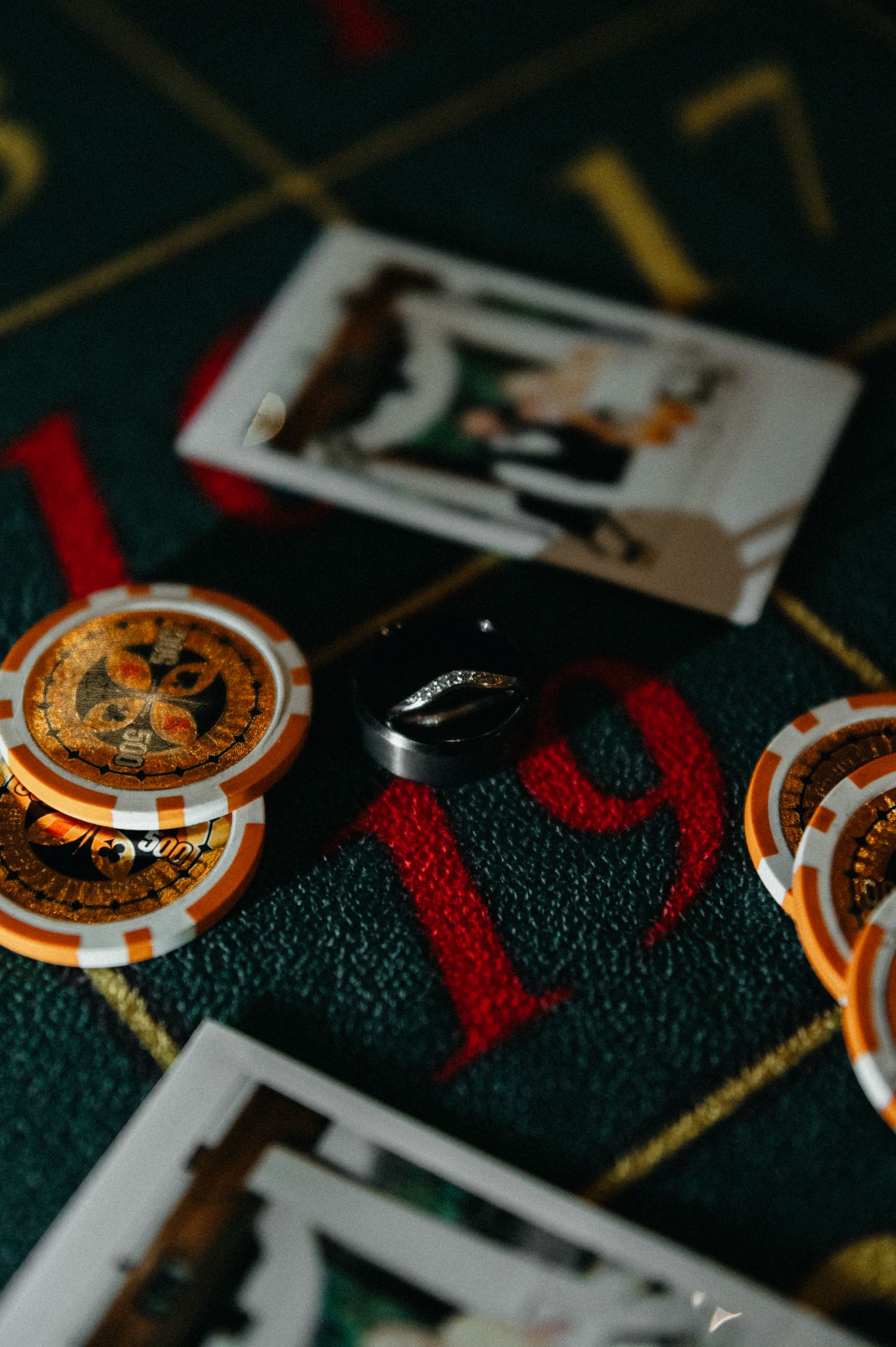 Close-up view of orange casino chips and playing cards on a dark green felt gaming table surface.