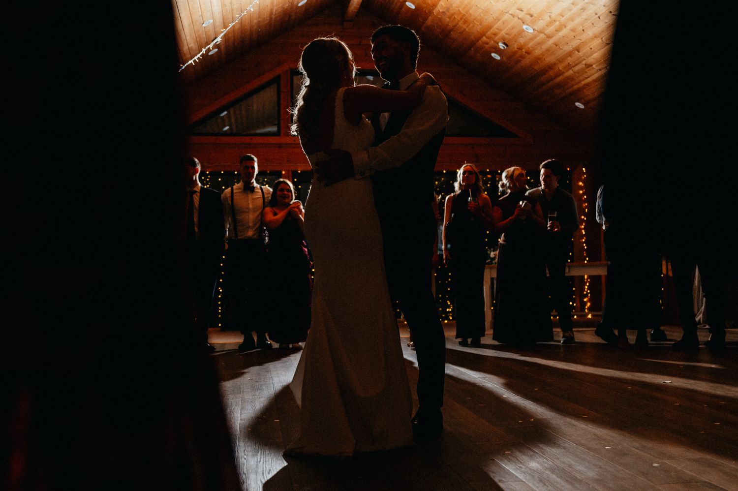 Wedding reception venue with warm wooden ceiling and romantic lighting.