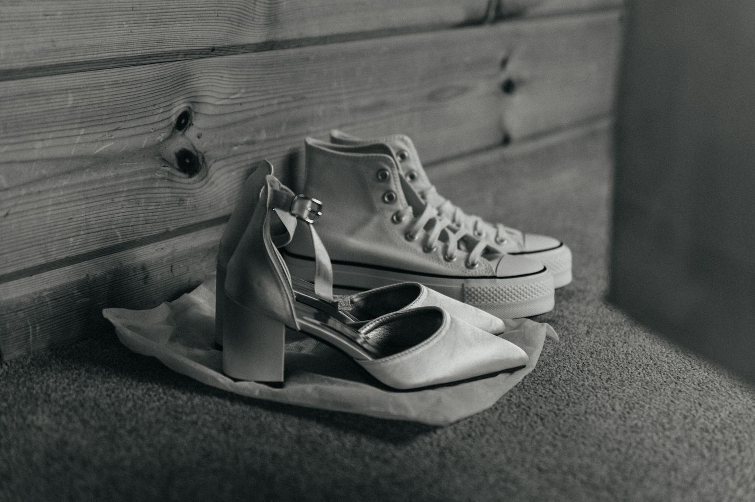 A series of black and white photographs showing classic canvas sneakers and boots arranged on a carpeted floor.