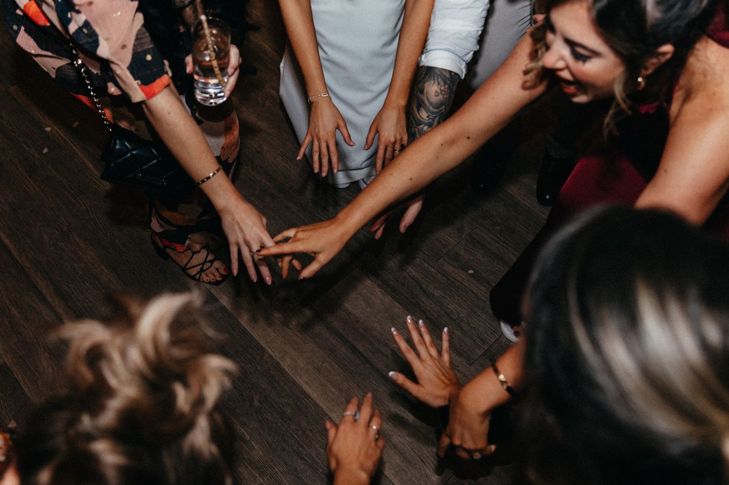 Overhead view of wedding guests dancing on dark wooden dance floor.