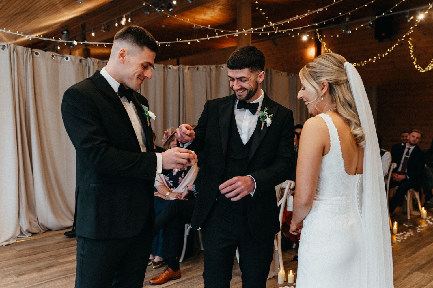 Couple embraces during emotional first look moment at wedding ceremony with string lights overhead.