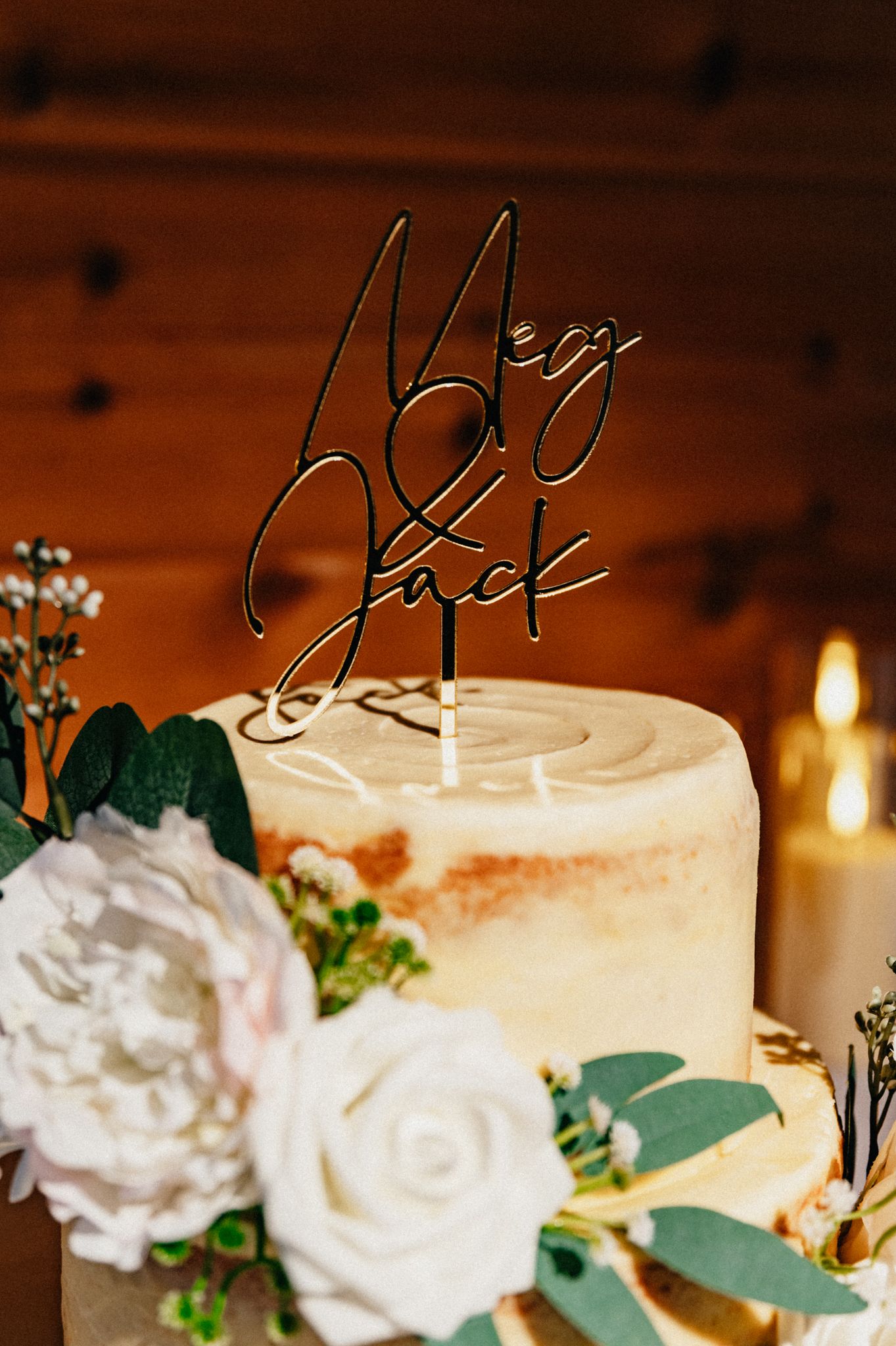 Elegant white wedding cake decorated with fresh flowers and eucalyptus leaves.