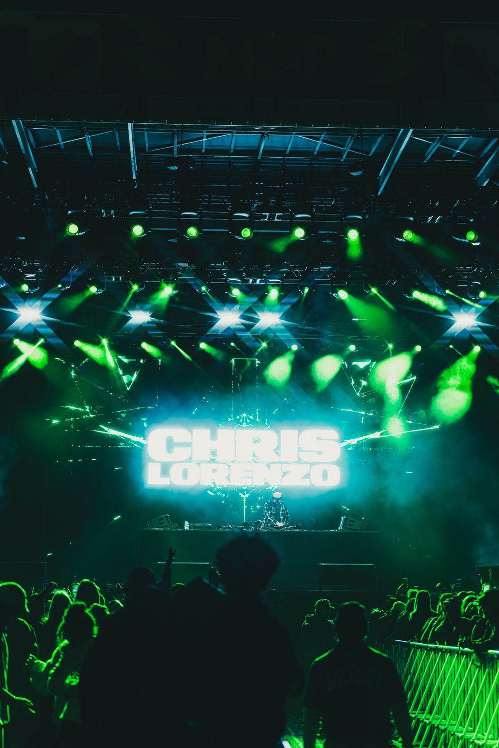 Concert stage lighting setup with bright green spotlights and illuminated text display creating an atmospheric nightclub ambiance.