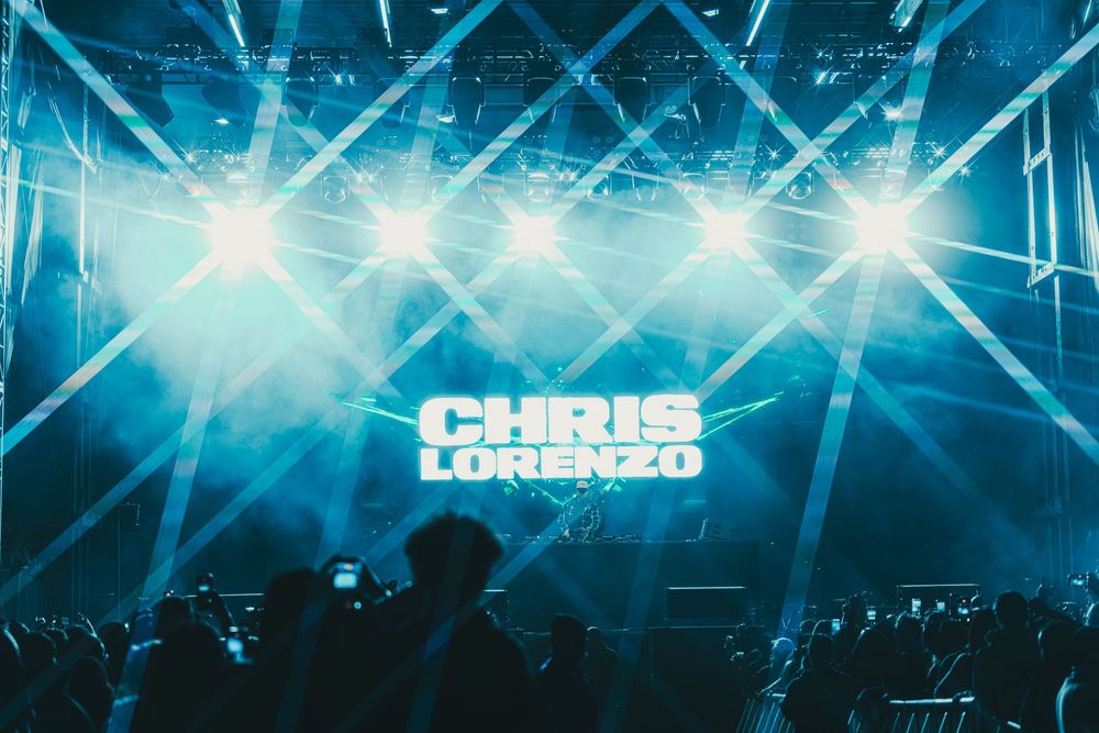 Concert stage lit with bright blue lights and fog effects creating an atmospheric nightclub environment.