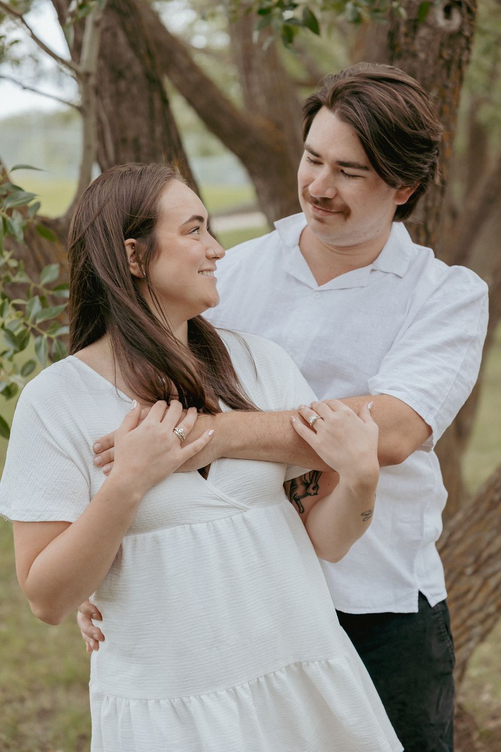 Romantic couple in white outfits sharing tender moments together in a natural outdoor setting.