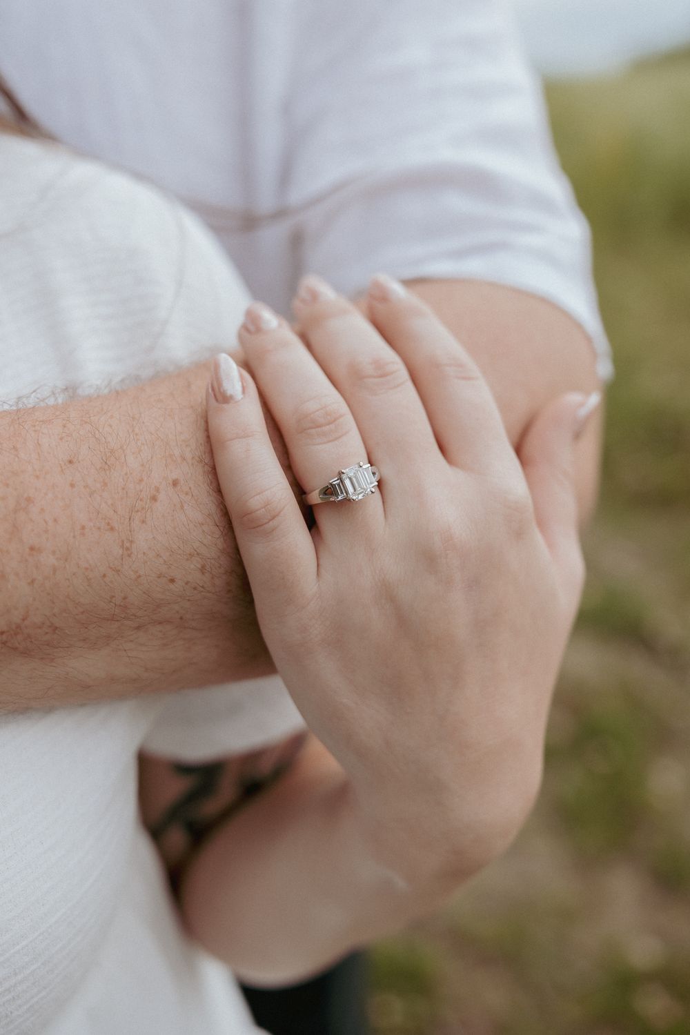 Close-up of hands showing engagement ring and intimate embrace.