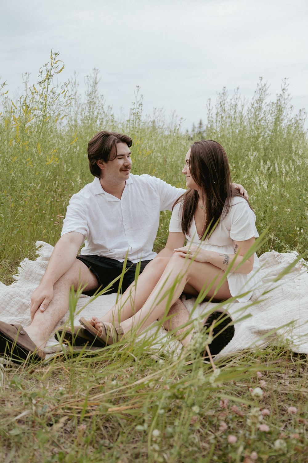 Couple relaxing together on a blanket in a wildflower meadow.