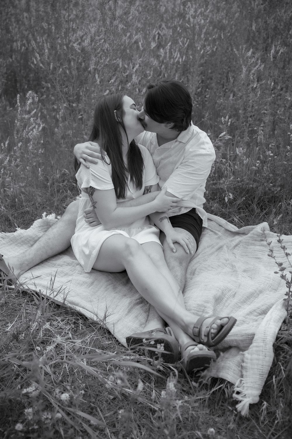 A romantic black and white photo sequence showing a couple lying in tall grass together.