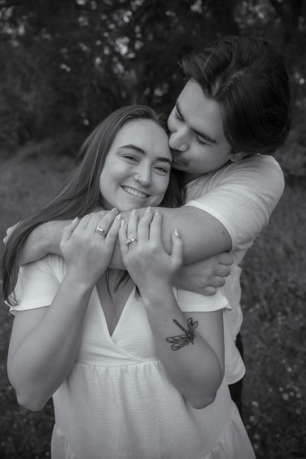 A tender moment between a couple wearing white clothing outdoors.