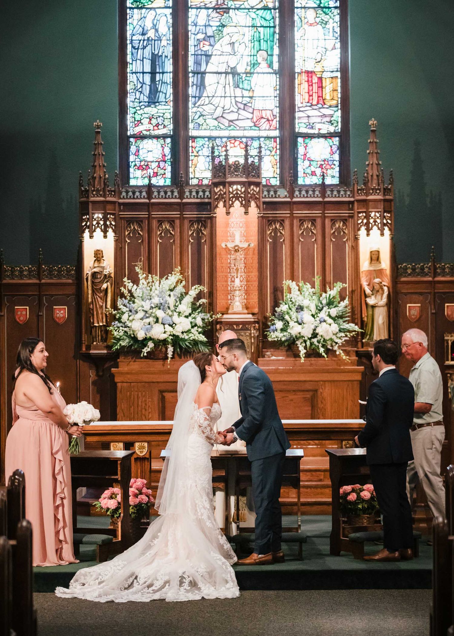 Bride and groom share their first kiss during a Catholic wedding ceremony at Saint Brigid Church in South Boston