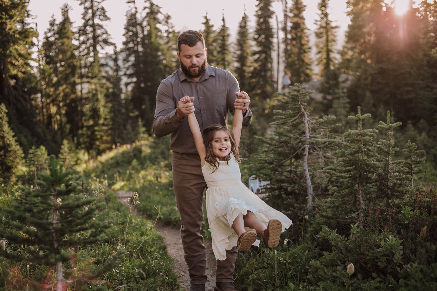 A Dad and daughter walk together during sunset among tall evergreen trees in a mountains of Artist Point, Near Mt. Baker Scenic Byway