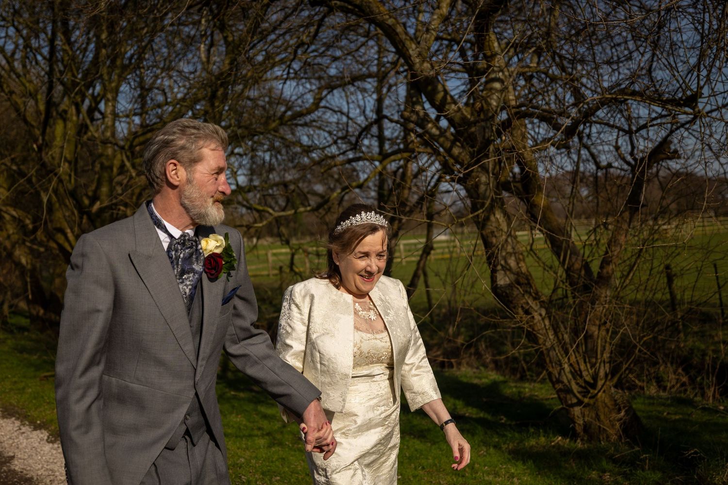 Dorothy and John walking together through the trees at Windmill Farm in Burscough during their relaxed Lancashire wedding day.