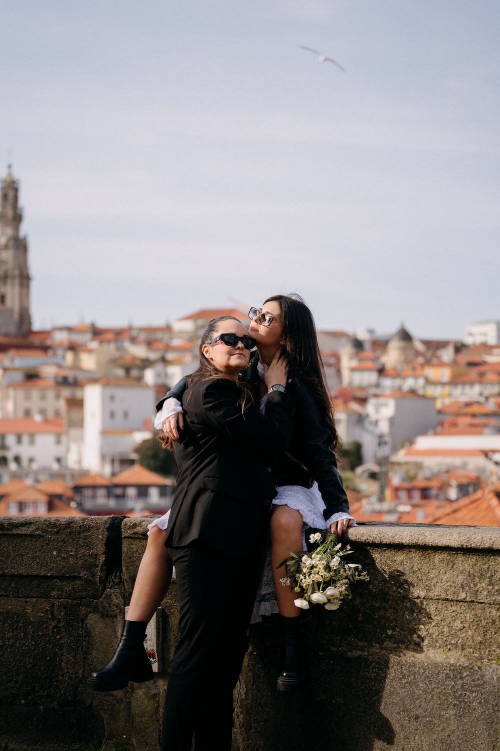 A romantic couple shares an intimate moment overlooking a scenic European cityscape with terracotta roofs.
