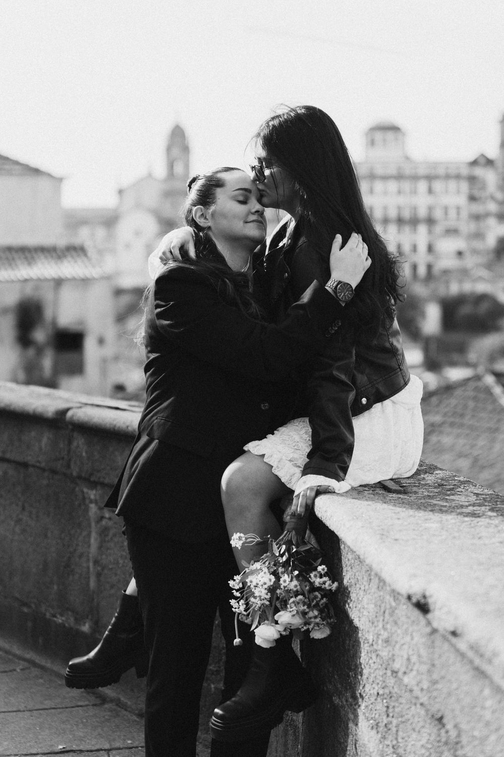 A romantic black and white photo series showing a couple embracing against a European cityscape backdrop.