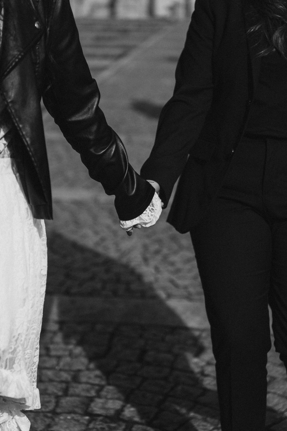 Black and white image of people's legs walking on cobblestone streets in an urban setting.