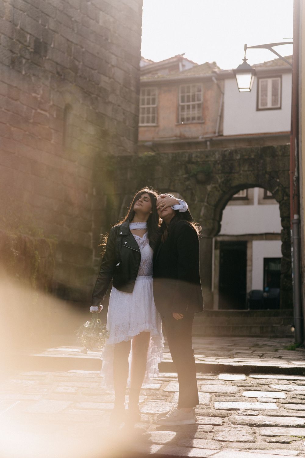 Silhouettes of people walking on cobblestone streets against historic buildings.