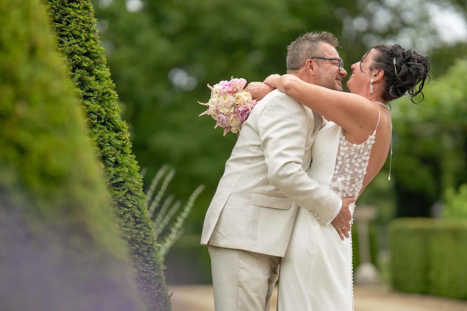 A couple in wedding attire share romantic moments in a lush garden setting during their celebration.