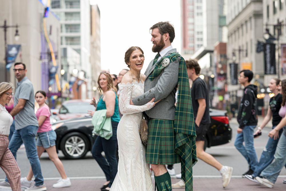 A couple dances together on a city street while other people walk past in the background.