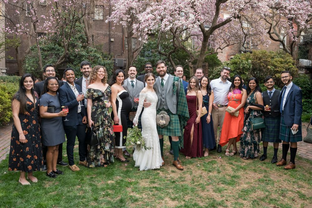 Wedding guests gather outdoors beneath blooming cherry blossom trees for a spring celebration.