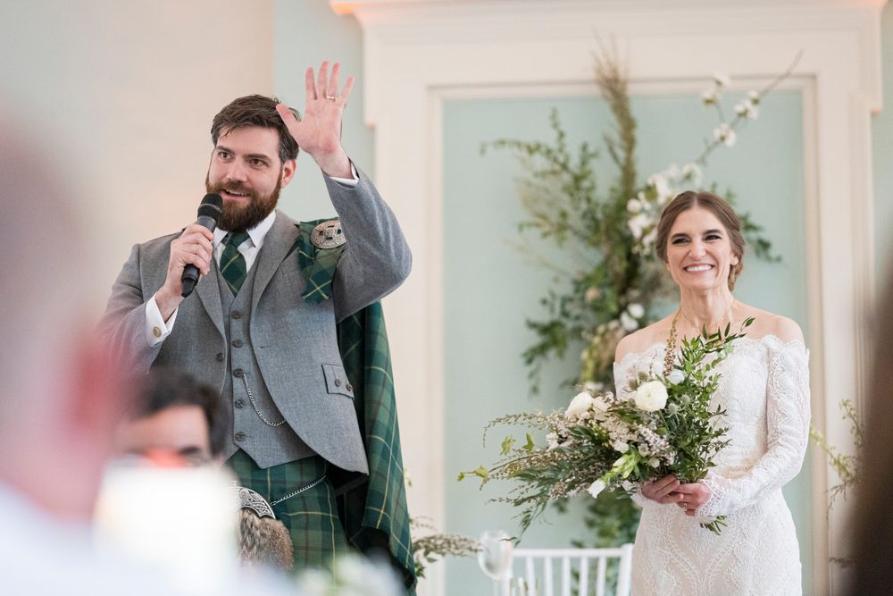 Wedding celebration scene with elegant floral arrangements and soft lighting in an indoor venue.