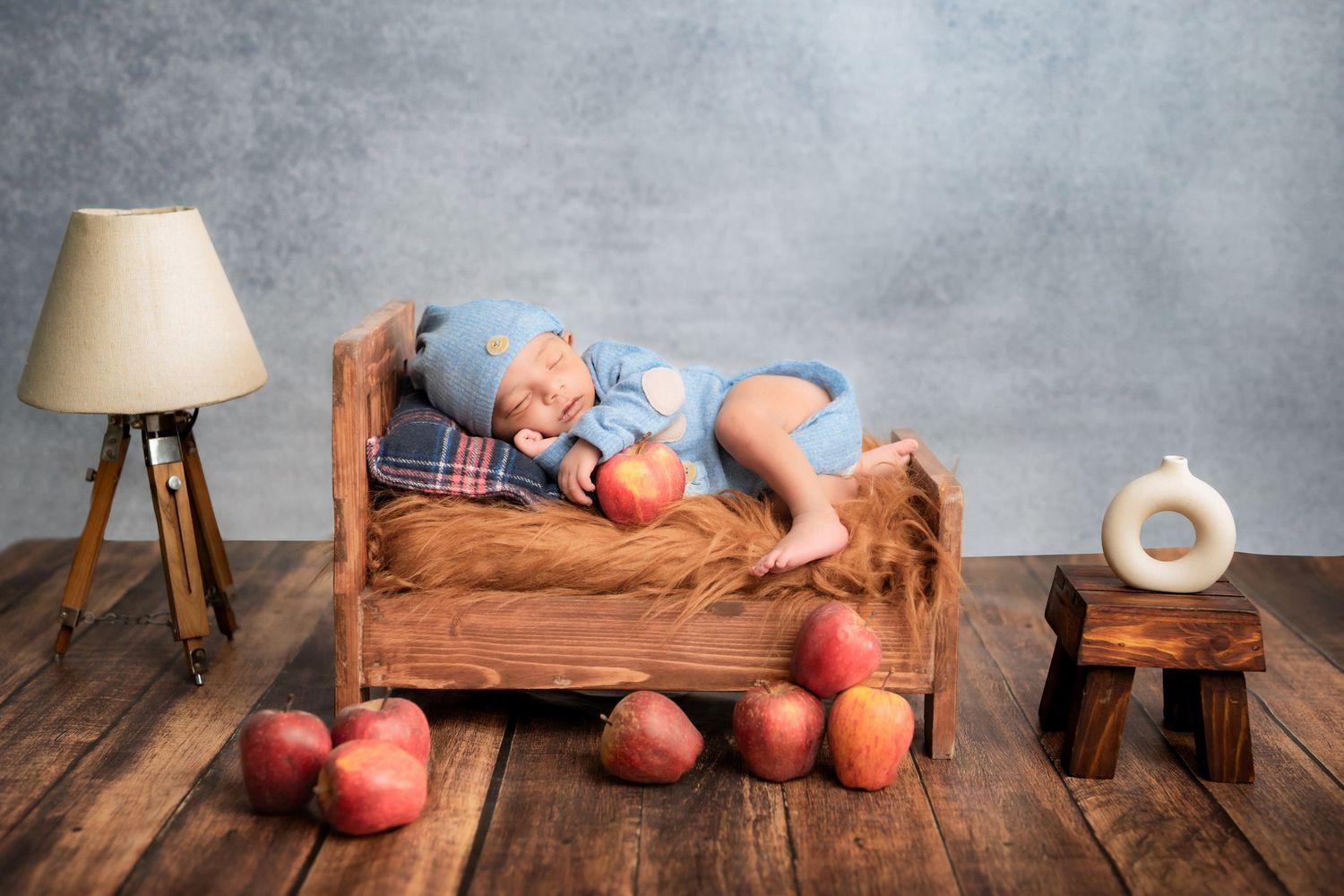 Newborn baby boy sleeping on wooden bed with apple props - best newborn photographer in Hyderabad by Bump To Baby by Sai Jyothi