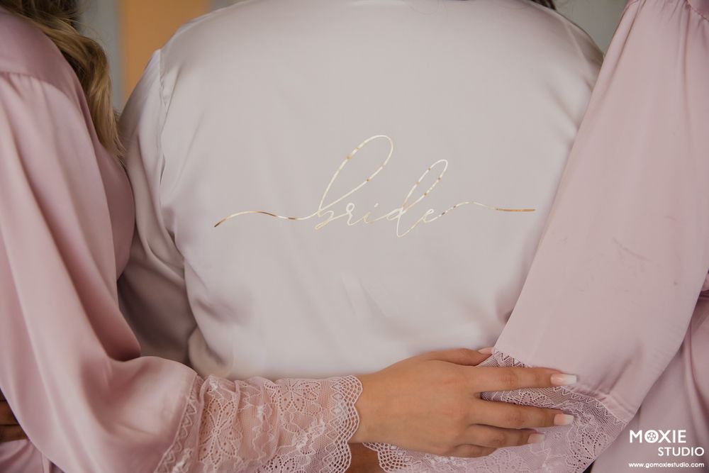 Close up detail of white bridal robe with elegant script embroidery.