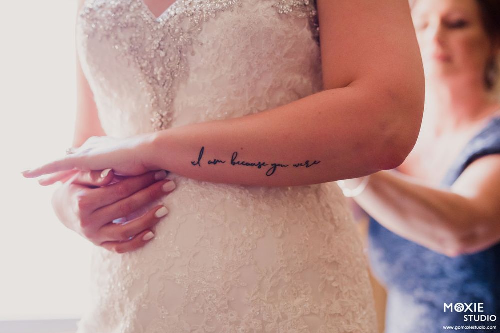 Close-up of a cursive tattoo reading 'I am enough' on someone's forearm during wedding preparations.
