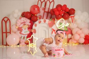 Pink and white balloon arch with decorative stars and party elements creates a festive backdrop.