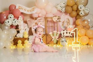 Pink and gold balloon arch with twinkle lights creates an elegant party backdrop for a special celebration.