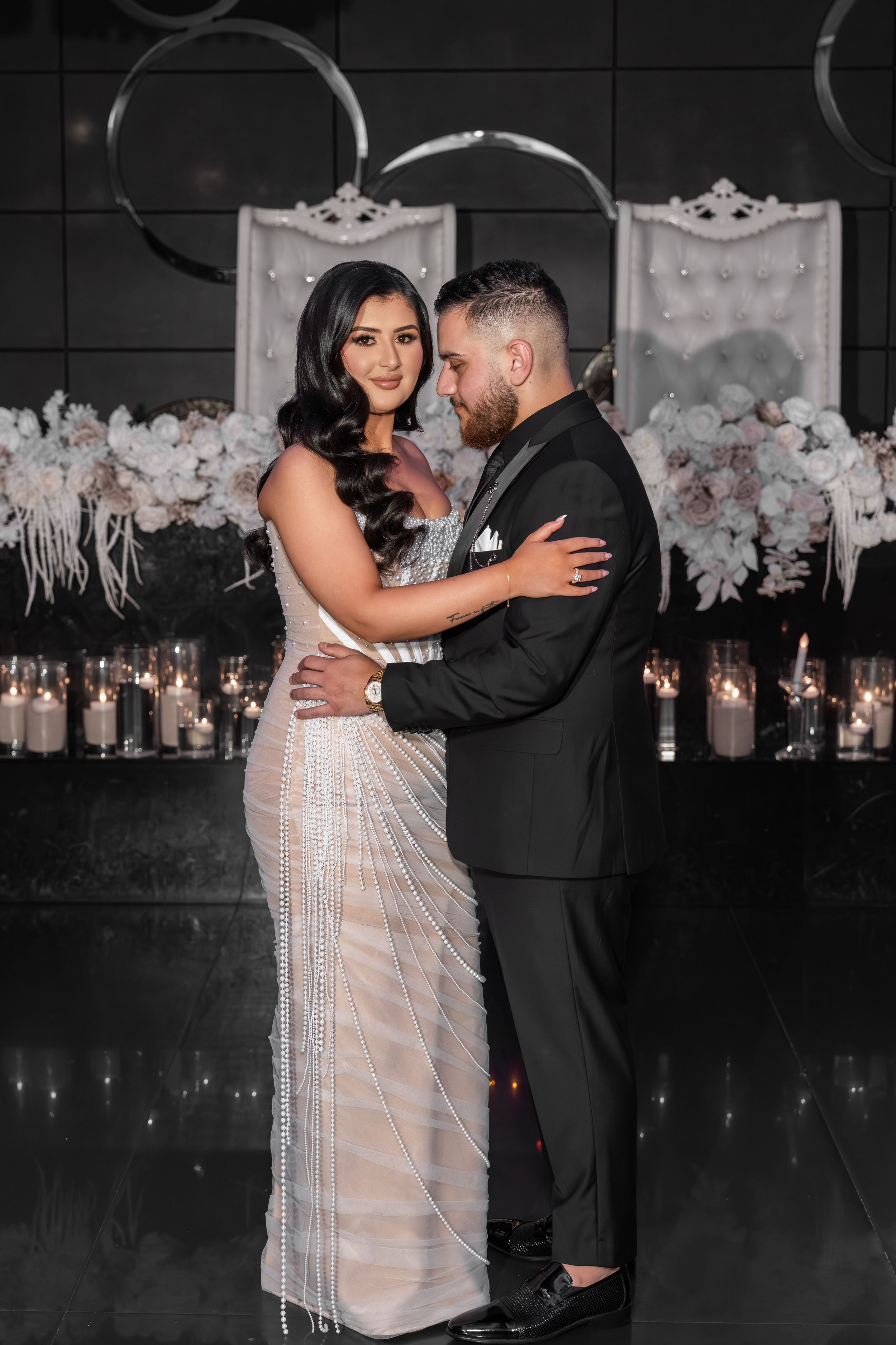 A couple shares their first dance at a wedding reception with romantic lighting and floral decorations in the background.
