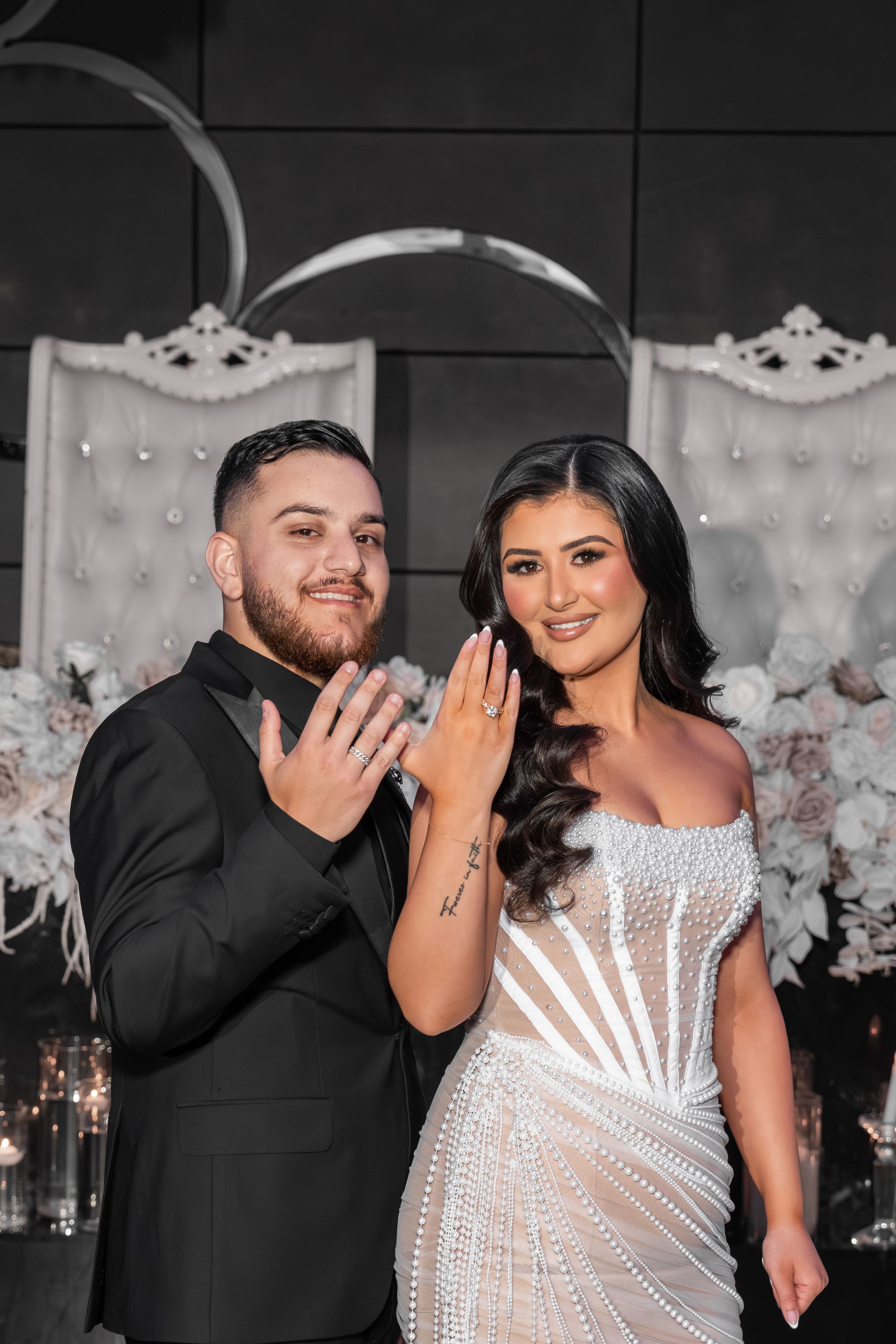 A couple poses playfully in a series of photos against a white tufted backdrop with floral decorations.