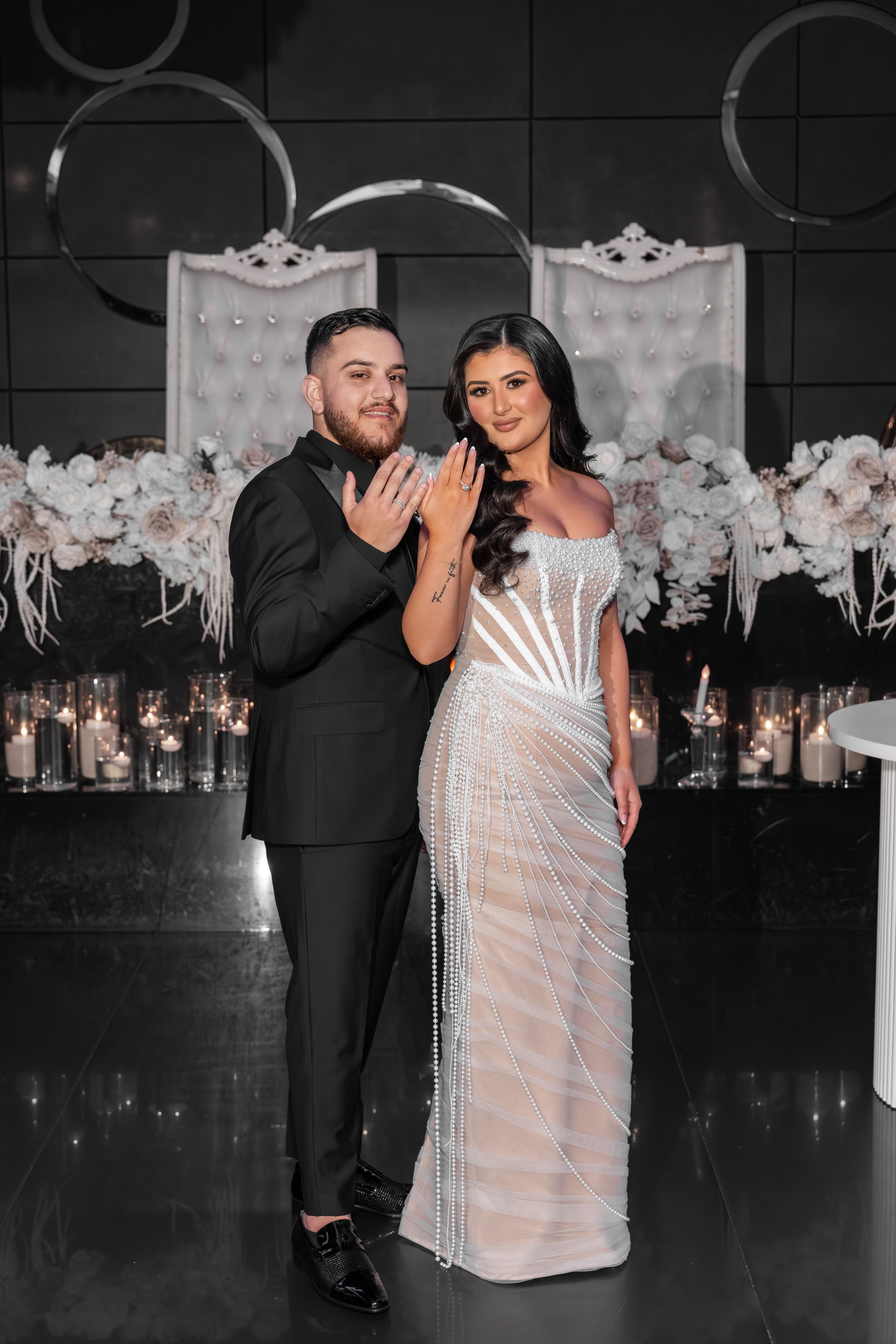A couple shares an intimate moment at their wedding reception with white floral decorations in the background.