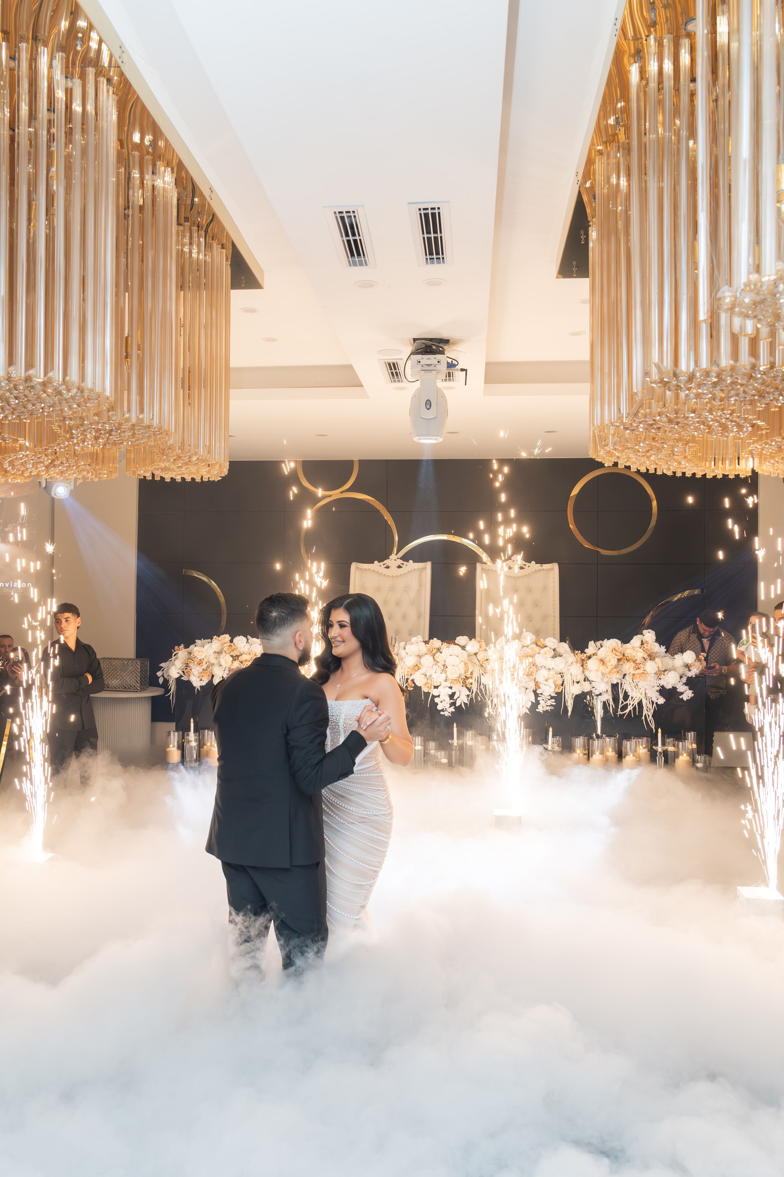 A romantic first dance at an elegant wedding reception with fog effects, crystal chandeliers and warm lighting.
