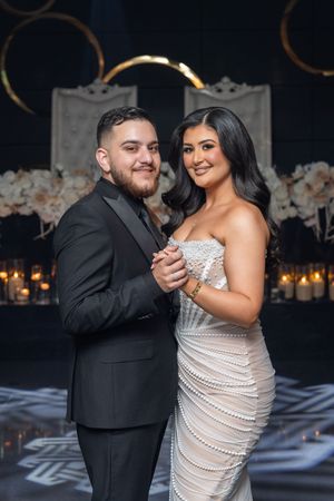 A couple shares a romantic dance moment at their wedding reception in formal attire.