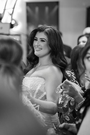 Black and white photo of a bride in a strapless beaded wedding gown smiling during a celebration.