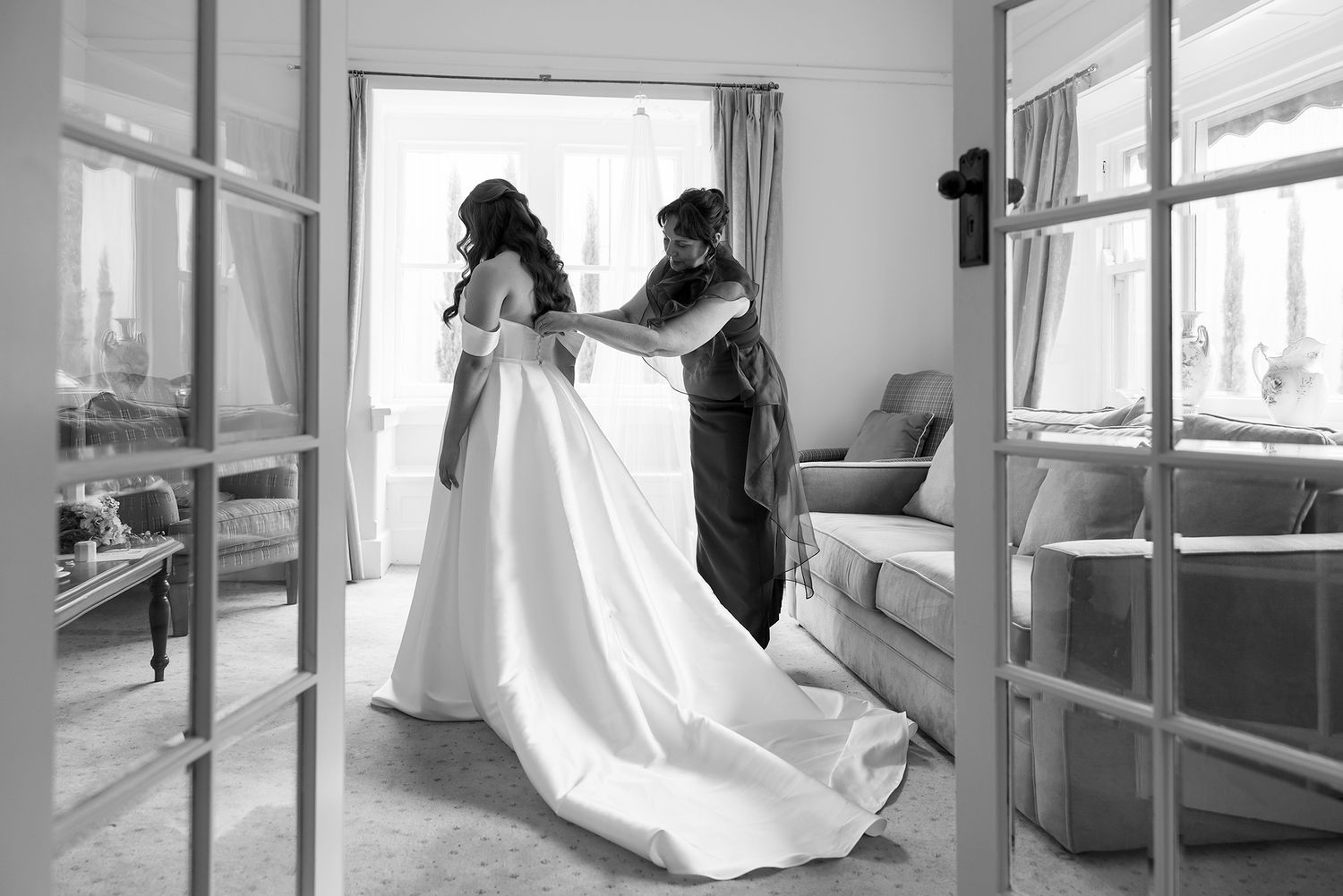 A tender black and white moment capturing final wedding dress preparations in a bright sunlit room at Brown Brothers Winery in Milawa.