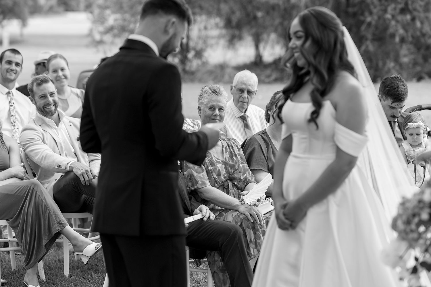 A black and white photo capturing an emotional outdoor wedding ceremony with seated guests looking on at Brown Brothers Winery.