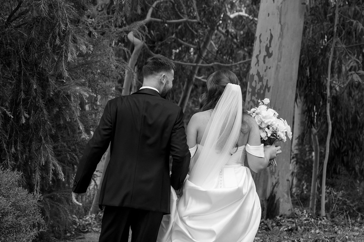 A newly married couple walks into a wooded area during their outdoor wedding ceremony at Brown Brothers Winery.