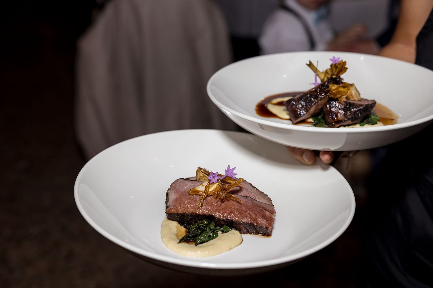 Two elegant plates of fine dining cuisine featuring medium-rare meat dishes with garnishes and sauces on white plates at Brown Brothers.